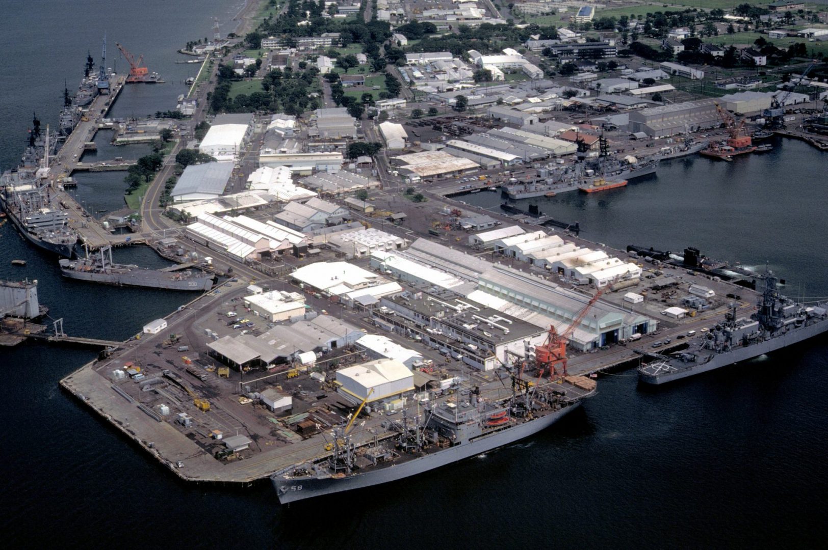 A view of the pier area with docked ships including the auxiliary stores ship USNS RIGEL (T-AF-58) and the nuclear-powered guided missile cruiser USS BAINBRIDGE (CGN-25) in the foreground. At left are the oiler USNS HASSAYAMPA (T-AO-145), the guided missile cruiser USS STERETT (CG-31), the guided missile destroyer USS HENRY B. WILSON (DDG-7) and the guided missile cruiser USS WILLIAM H. STANDLEY (CG-32).